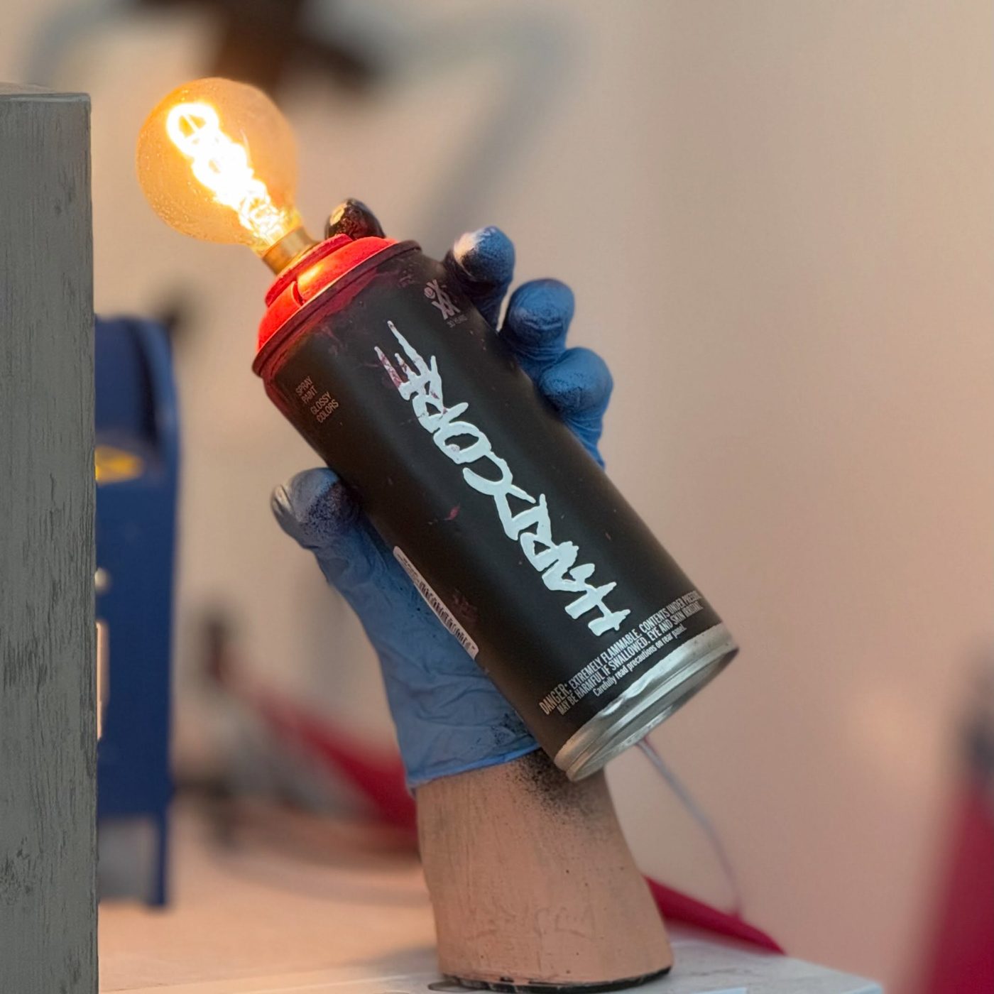 Black spray can lamp held upside down by a gloved plaster hand