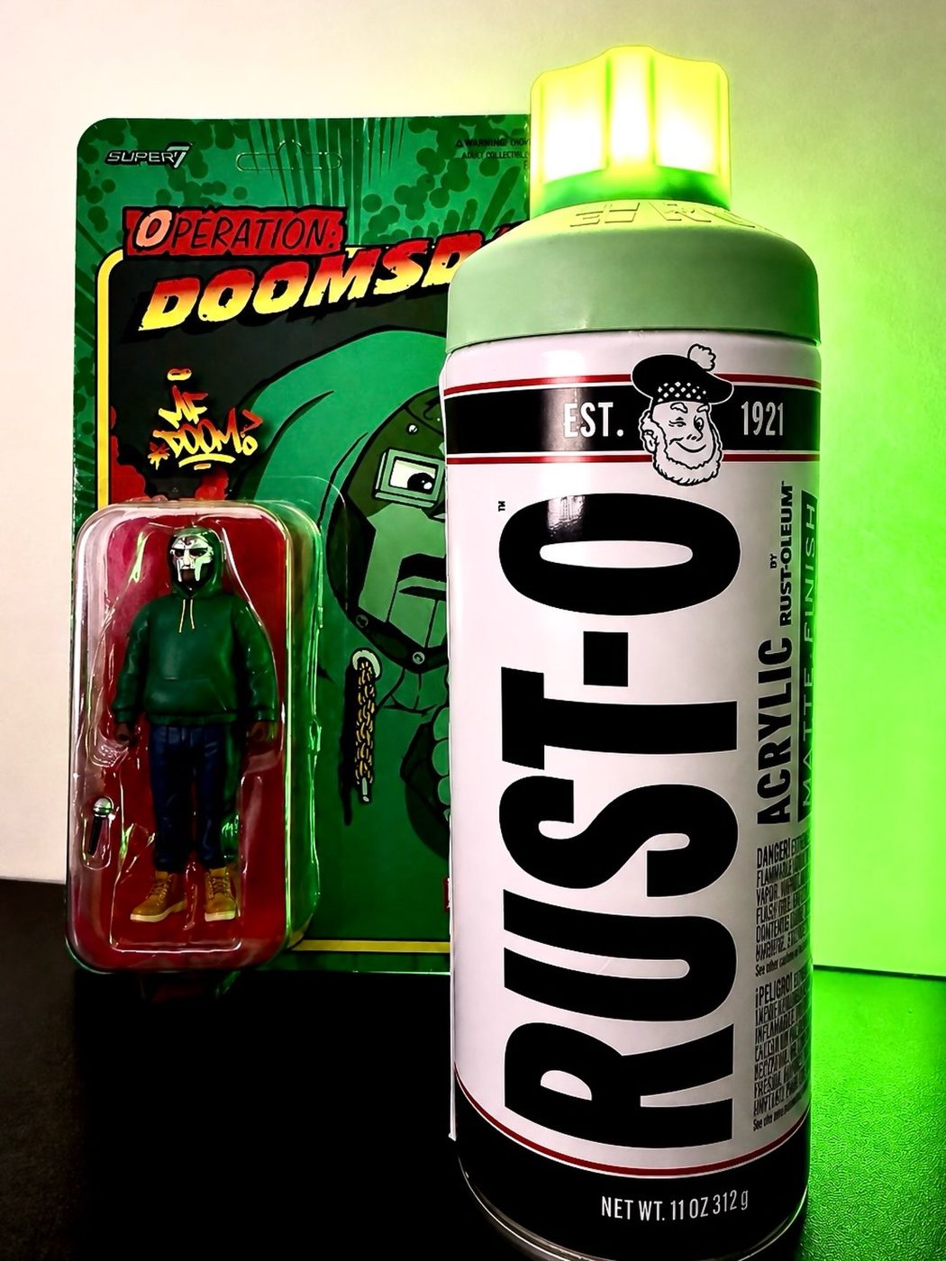 Glowing green spray can lamp next to an MF DOOM action figure on its card