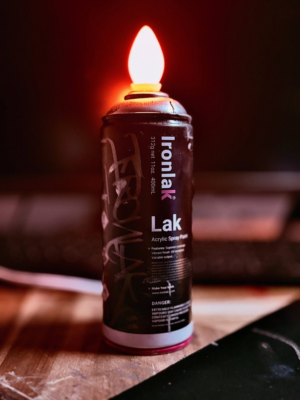 Black Ironlak spray can turned into a lamp with a glowing candle-flame bulb
