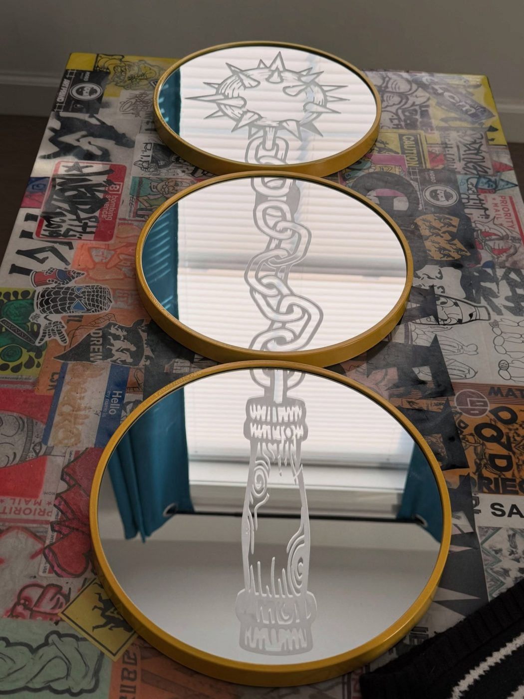 Three round gold-framed mirrors etched with a spiked mace on a chain