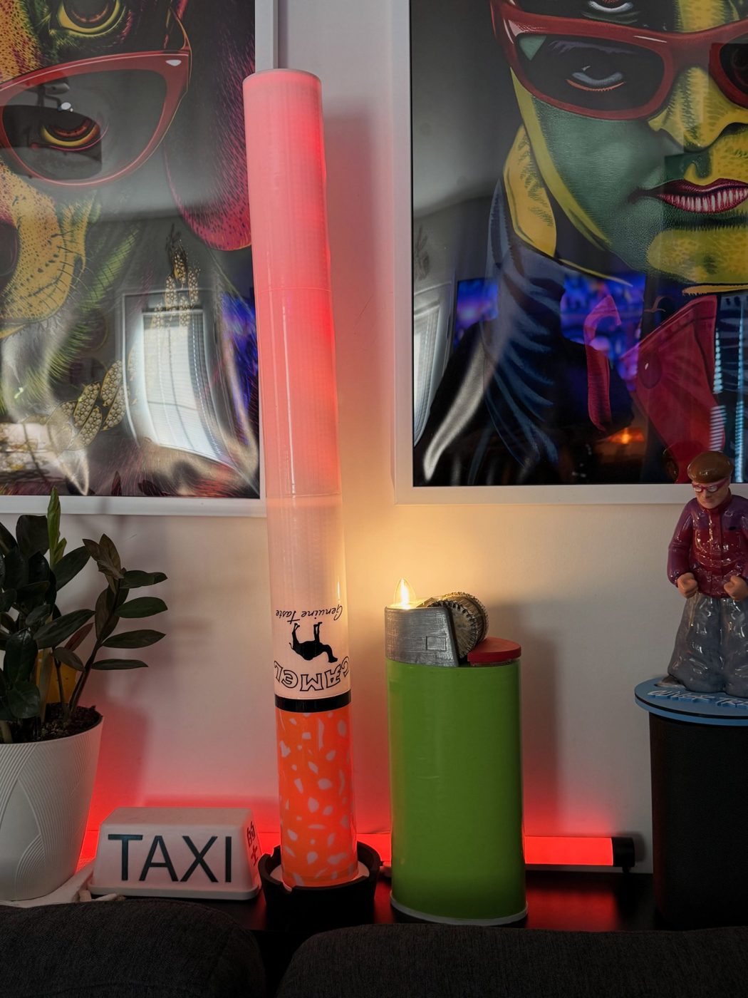 Cigarette lamp and lighter lamp on a shelf under colorful framed portraits
