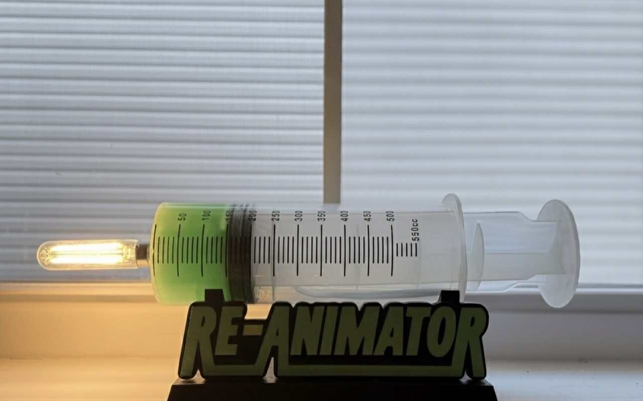 Giant syringe lamp with glowing green liquid on a Re-Animator stand